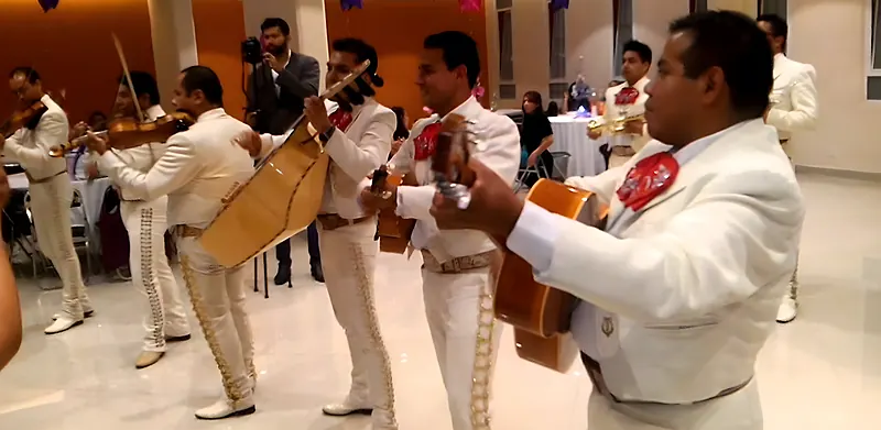 Músicos de mariachi con traje blanco tocando en un salón para serenatas en Bosque de Modelia